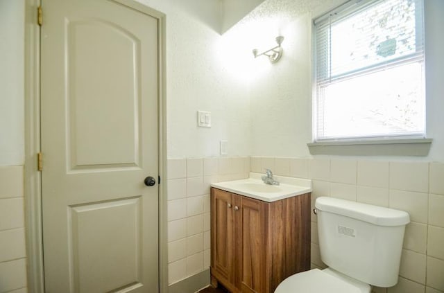 bathroom featuring vanity, toilet, and tile walls