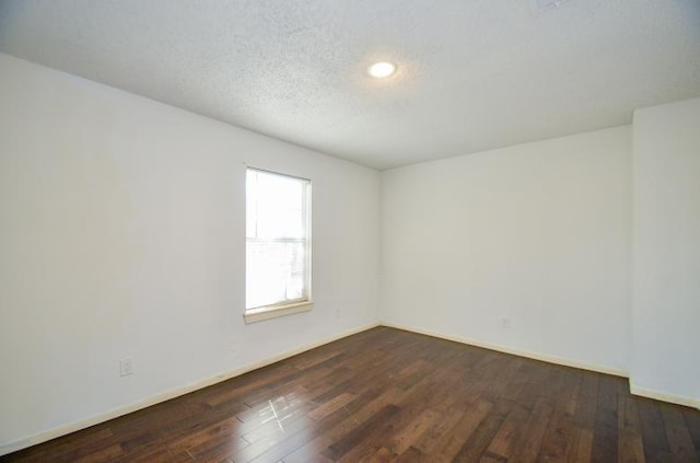 empty room featuring dark hardwood / wood-style floors and a textured ceiling