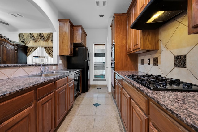 kitchen featuring sink, dark stone countertops, backsplash, and black appliances