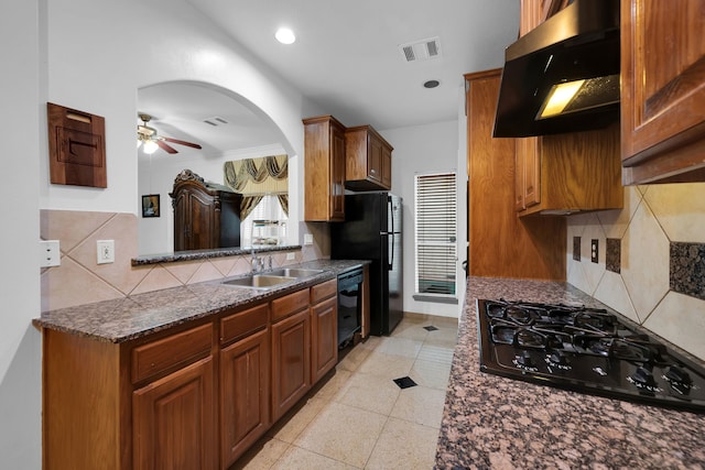 kitchen featuring ventilation hood, sink, decorative backsplash, ceiling fan, and black appliances