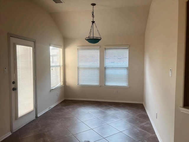 unfurnished dining area with vaulted ceiling and dark tile patterned floors