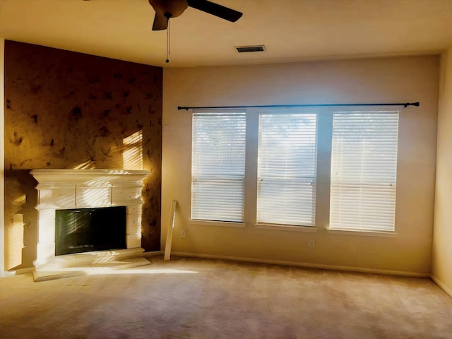 unfurnished living room with a fireplace, light colored carpet, and ceiling fan