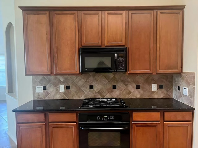 kitchen with tasteful backsplash, dark stone countertops, and black appliances