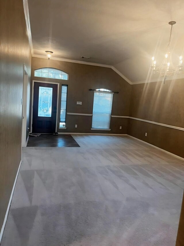 foyer entrance with lofted ceiling, ornamental molding, carpet flooring, and a notable chandelier