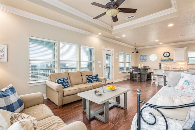 living room featuring dark hardwood / wood-style flooring, crown molding, plenty of natural light, and ceiling fan