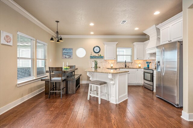 kitchen featuring white cabinetry, light stone counters, a breakfast bar area, and appliances with stainless steel finishes