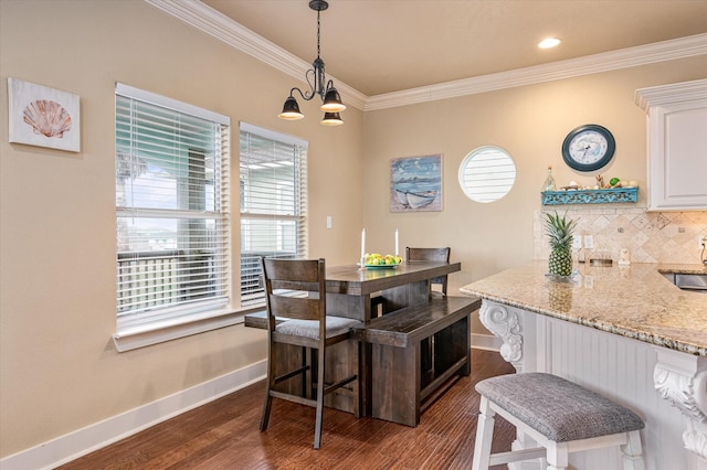 dining area with sink, a notable chandelier, crown molding, and dark hardwood / wood-style floors