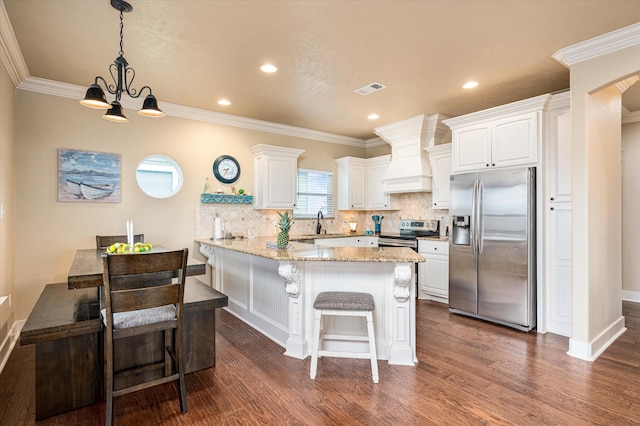 kitchen featuring custom exhaust hood, hanging light fixtures, stainless steel appliances, light stone countertops, and white cabinets