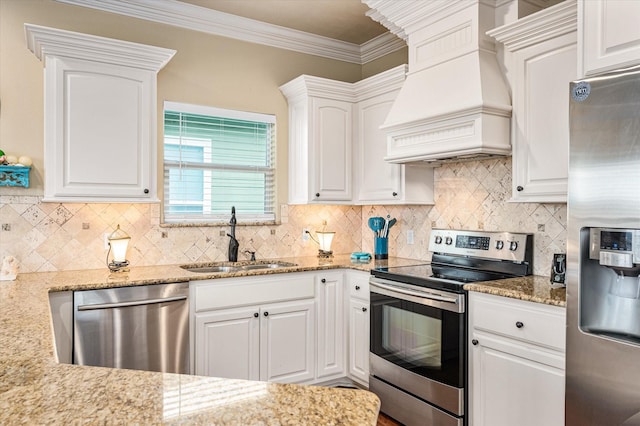 kitchen featuring stainless steel appliances, premium range hood, a sink, white cabinets, and light stone countertops