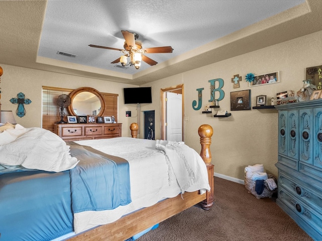 carpeted bedroom featuring ceiling fan, a tray ceiling, and a textured ceiling