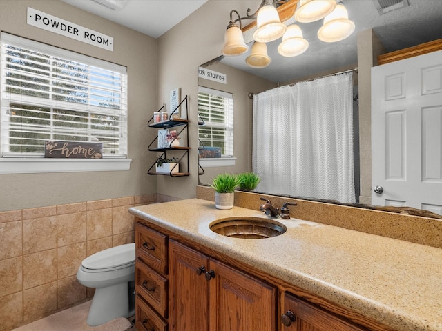 bathroom with vanity, toilet, and tile walls