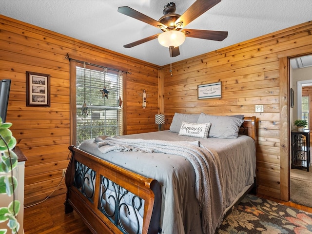 bedroom with ceiling fan, dark hardwood / wood-style floors, multiple windows, and a textured ceiling