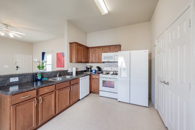 kitchen featuring sink, white appliances, ceiling fan, dark stone countertops, and kitchen peninsula