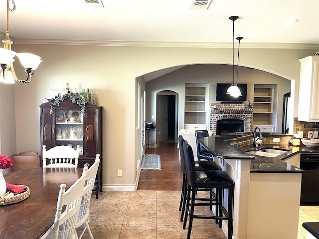 kitchen with black dishwasher, pendant lighting, white cabinets, and a kitchen breakfast bar