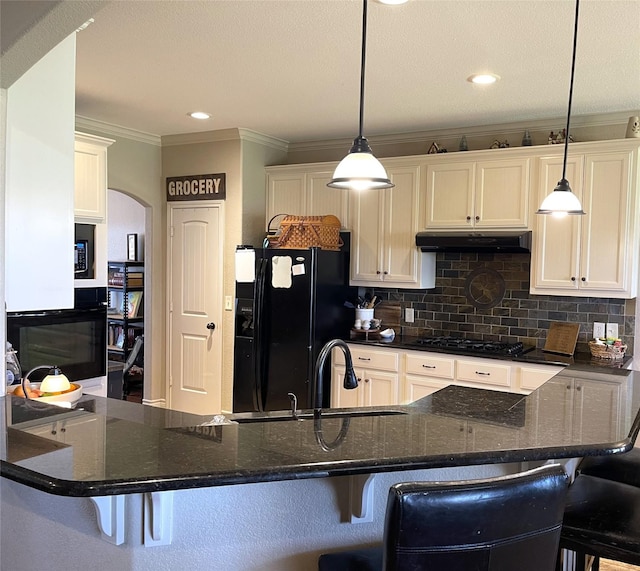 kitchen with pendant lighting, sink, white cabinets, a kitchen breakfast bar, and black appliances