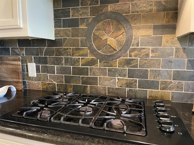 interior details featuring tasteful backsplash, black gas stovetop, dark stone countertops, and white cabinets