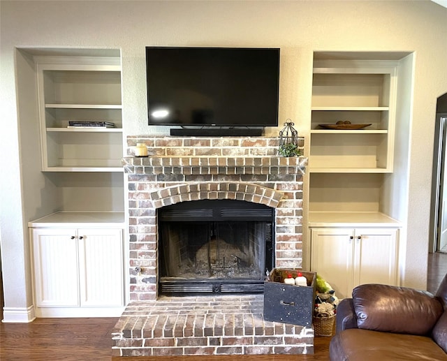 interior details featuring a brick fireplace, hardwood / wood-style flooring, and built in shelves