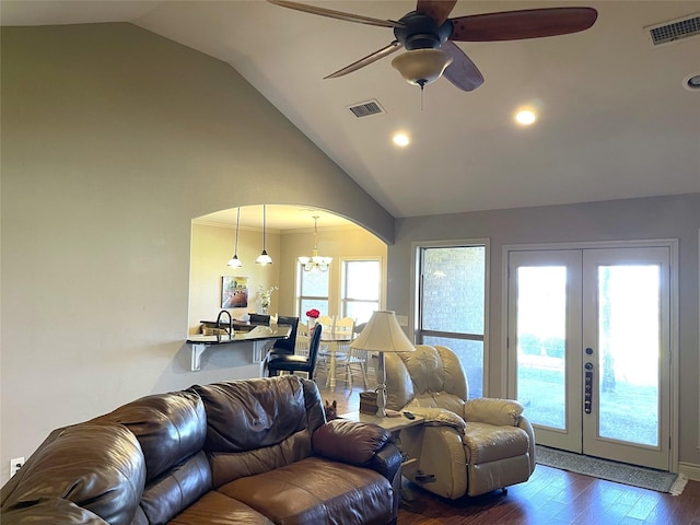 living room featuring dark wood-type flooring, ceiling fan with notable chandelier, high vaulted ceiling, and french doors