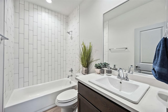 full bathroom featuring tiled shower / bath, vanity, and toilet