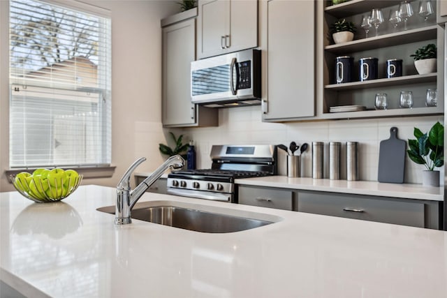 kitchen with appliances with stainless steel finishes, sink, gray cabinetry, and decorative backsplash