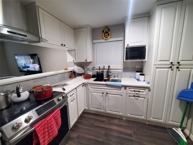 kitchen featuring black microwave, sink, white cabinets, electric range, and wall chimney exhaust hood