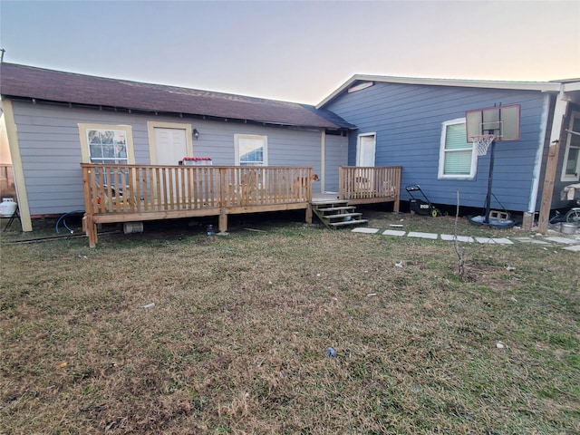 back house at dusk with a deck and a lawn