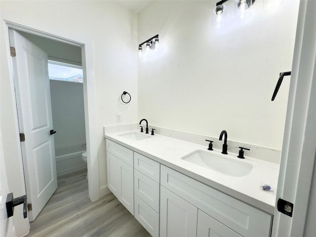 bathroom featuring vanity, a tub to relax in, hardwood / wood-style floors, and toilet