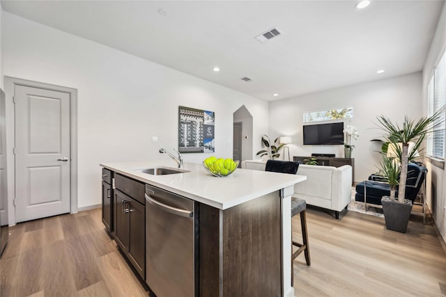 kitchen featuring sink, light hardwood / wood-style flooring, a kitchen island with sink, dark brown cabinets, and stainless steel dishwasher