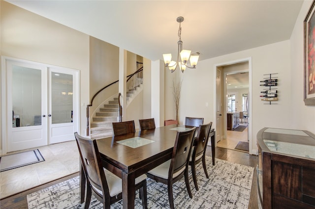 dining area with light hardwood / wood-style flooring, french doors, and a chandelier