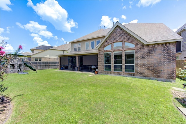 rear view of property featuring a playground, a yard, and a patio area