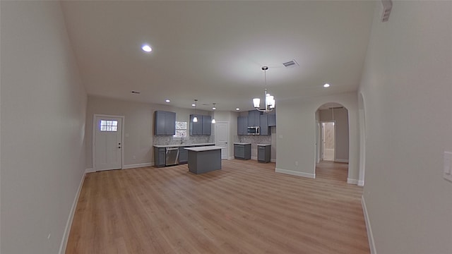 kitchen featuring wood-type flooring, decorative light fixtures, a center island, stainless steel appliances, and decorative backsplash