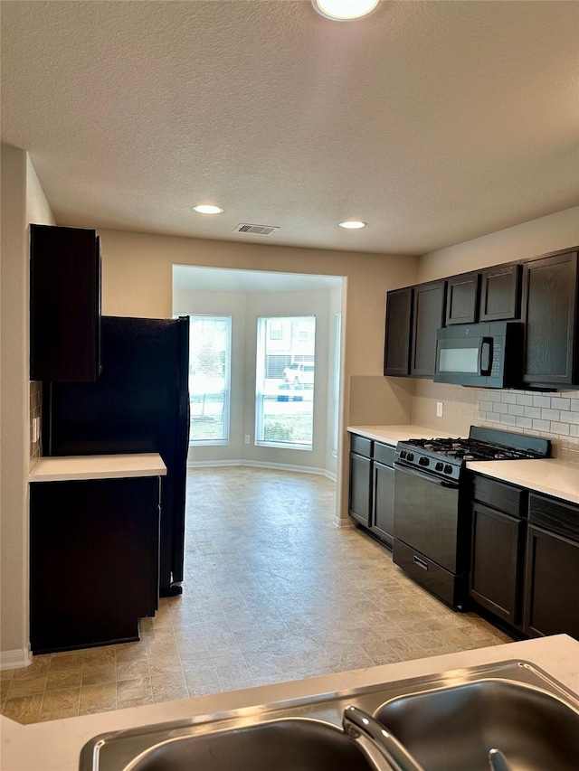 kitchen featuring dark brown cabinets, backsplash, a textured ceiling, and black appliances