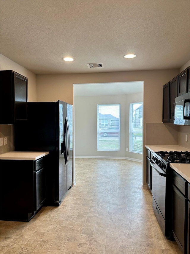 kitchen featuring decorative backsplash, black appliances, and a textured ceiling