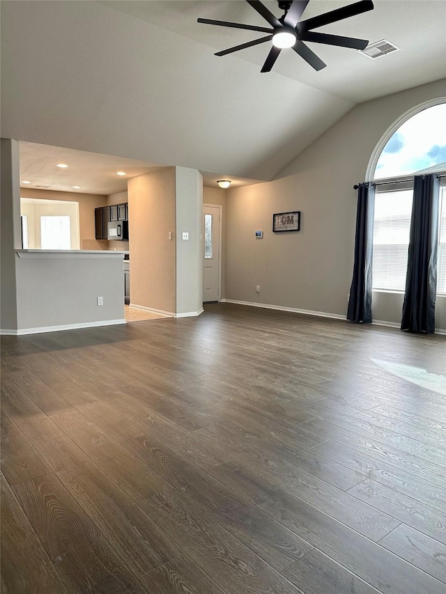 unfurnished living room with dark hardwood / wood-style flooring, a wealth of natural light, ceiling fan, and vaulted ceiling