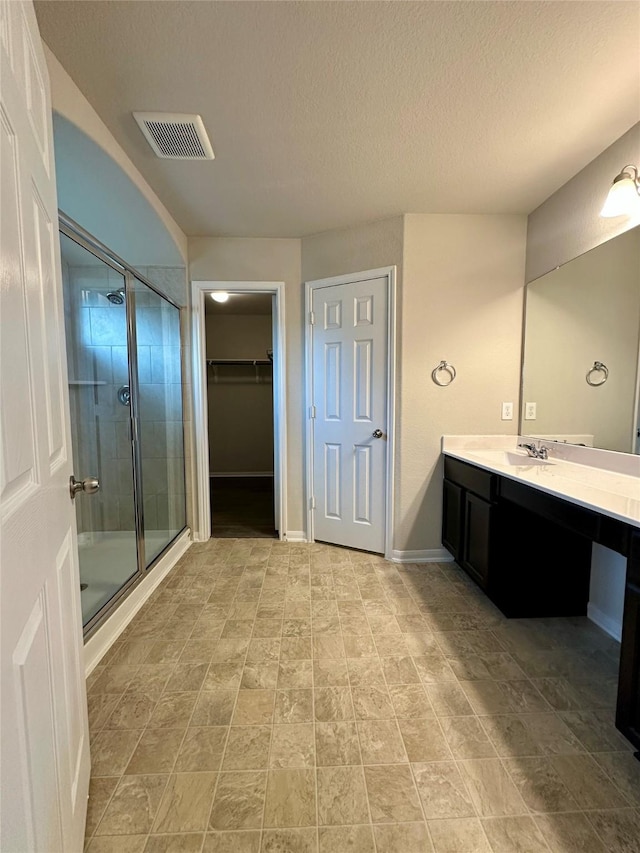 bathroom featuring an enclosed shower, vanity, and a textured ceiling