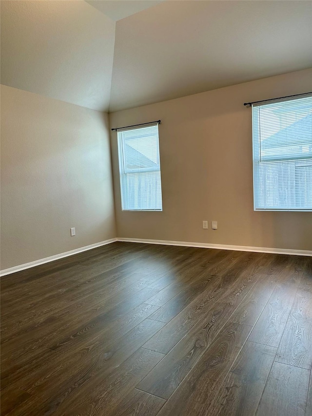 spare room featuring lofted ceiling and dark wood-type flooring