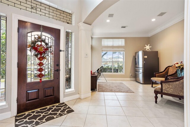 tiled foyer entrance with ornamental molding and decorative columns