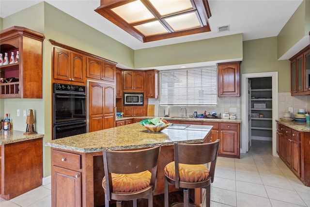 kitchen featuring a kitchen island, a breakfast bar, built in appliances, and sink