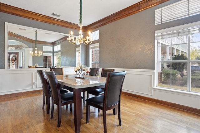 dining space featuring ornamental molding, a chandelier, and light hardwood / wood-style floors