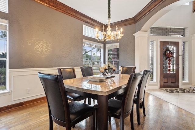 dining space with a notable chandelier, ornamental molding, and light wood-type flooring