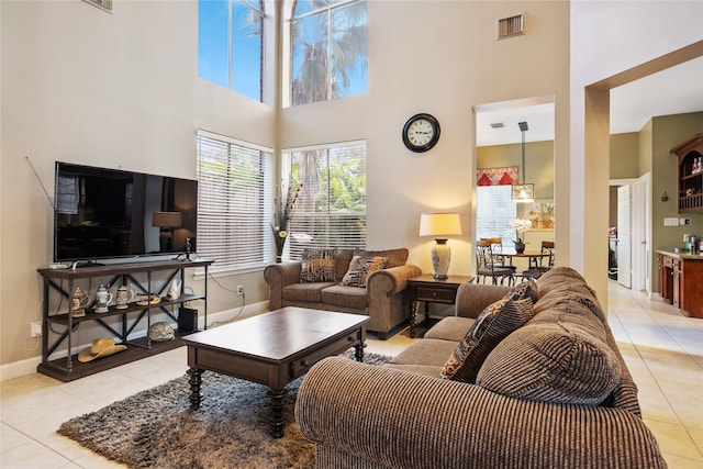 living room with a towering ceiling and light tile patterned floors