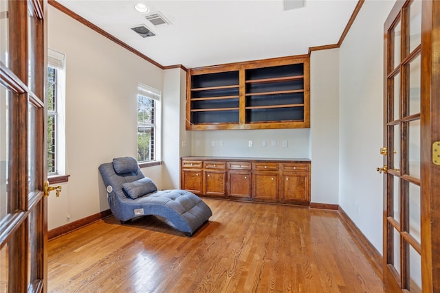 sitting room with ornamental molding and light hardwood / wood-style flooring