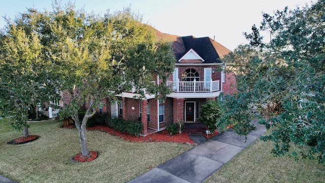 view of front of property featuring a balcony and a front lawn