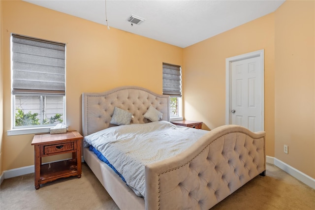 bedroom with multiple windows and light colored carpet