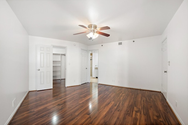 unfurnished bedroom featuring dark wood-type flooring, ceiling fan, a spacious closet, and a closet