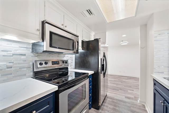 kitchen featuring stainless steel appliances, blue cabinetry, white cabinets, and decorative backsplash