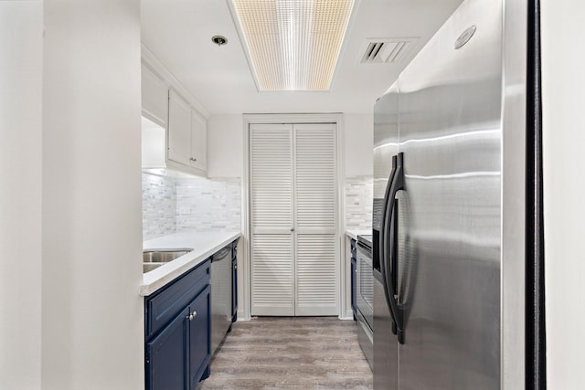 kitchen featuring tasteful backsplash, light hardwood / wood-style flooring, stainless steel appliances, and blue cabinetry