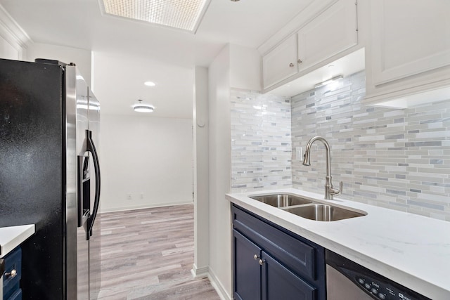 kitchen featuring sink, light wood-type flooring, stainless steel appliances, decorative backsplash, and white cabinets