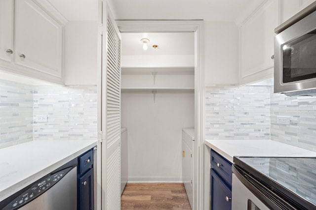 kitchen with white cabinetry, appliances with stainless steel finishes, blue cabinets, and backsplash