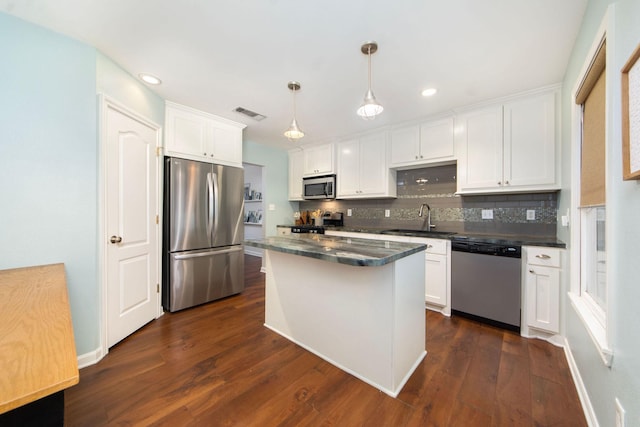 kitchen featuring hanging light fixtures, stainless steel appliances, sink, and white cabinets